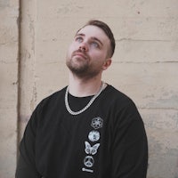 a man wearing a black sweatshirt looking up at a wall